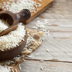 Drewniana miska pełna ryżu, z drewnianą łyżką. Czy pies może jeść ryż? Tak, gotowany ryż jest bezpieczny dla psów.