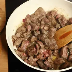 Smażona wątróbka na patelni, obok posiekana cebula. Czy pies może jeść wątróbkę? Tak, ale z umiarem.