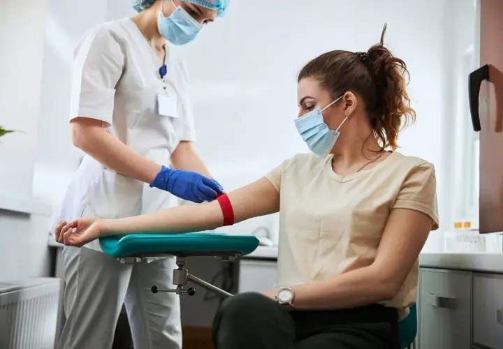 Pielęgniarka przygotowuje pacjentkę do pobrania krwi. Badanie może pomóc zdiagnozować leukopenię, czyli zbyt niski poziom białych krwinek.