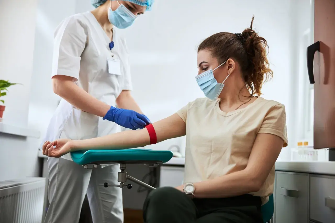 Pielęgniarka przygotowuje pacjentkę do pobrania krwi. Badanie może pomóc zdiagnozować leukopenię, czyli zbyt niski poziom białych krwinek.